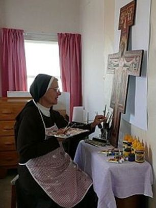 Sister with an artist's palette working on a crucifix painting