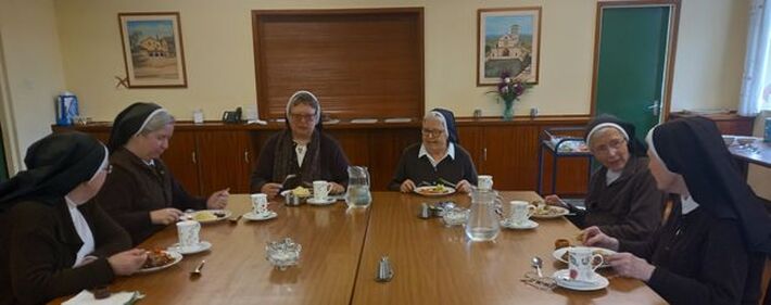 Sisters sitting round a table at a community meal