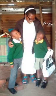 Sister hugs a couple of school children in their uniforms