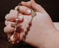 Hands holding a wooden rosary beads