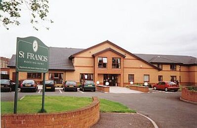 Photo of St Francis Care Home a two storey brickbuilding with cars parked at the front