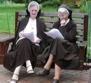 Two Sisters onan outside bench reading papers